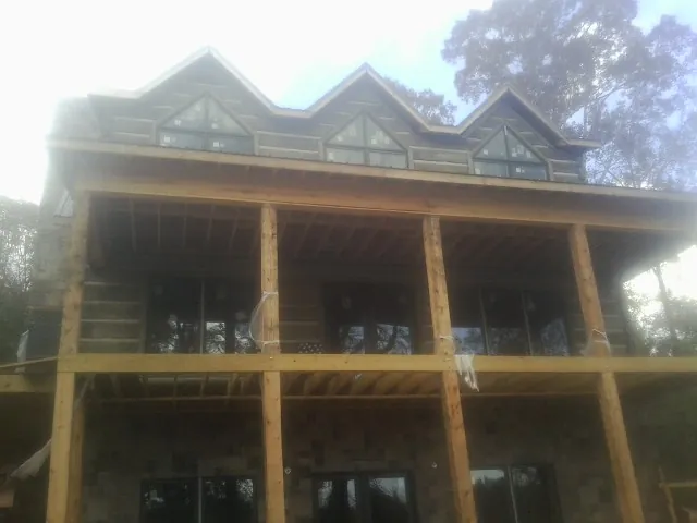 Dormers and porch framing on a large log home under construction — Roof Coating work by our crew in Brewster