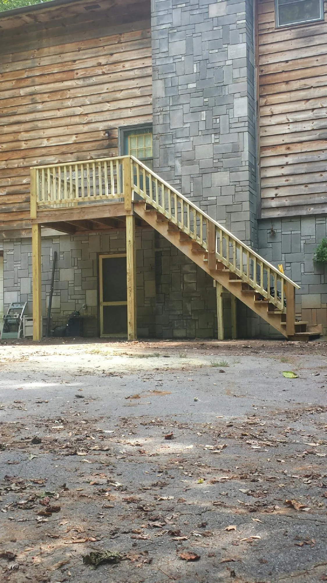 New pressure treated deck and stair landing on a log home in Brewster